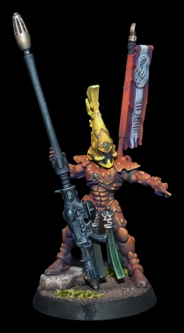 Aeldari Fire Dragon Exarch in orangeroter Rüstung mit gelbem Helmkamm und dunkler Feuerdrachen-Waffe auf steiniger Base vor schwarzem Hintergrund