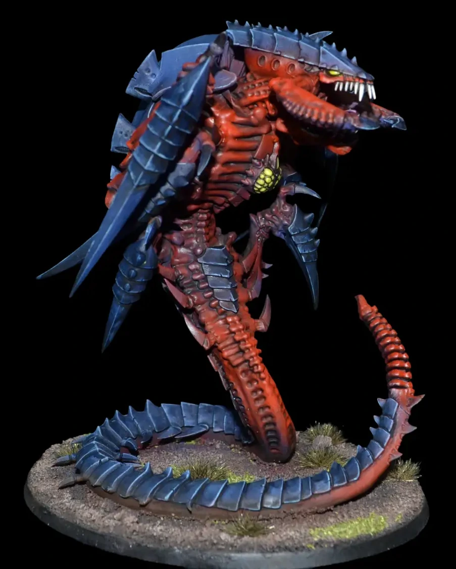 Trygon mit rotem Körper, blauem Chitinpanzer und langem eingerolltem Schwanz auf felsiger Base
